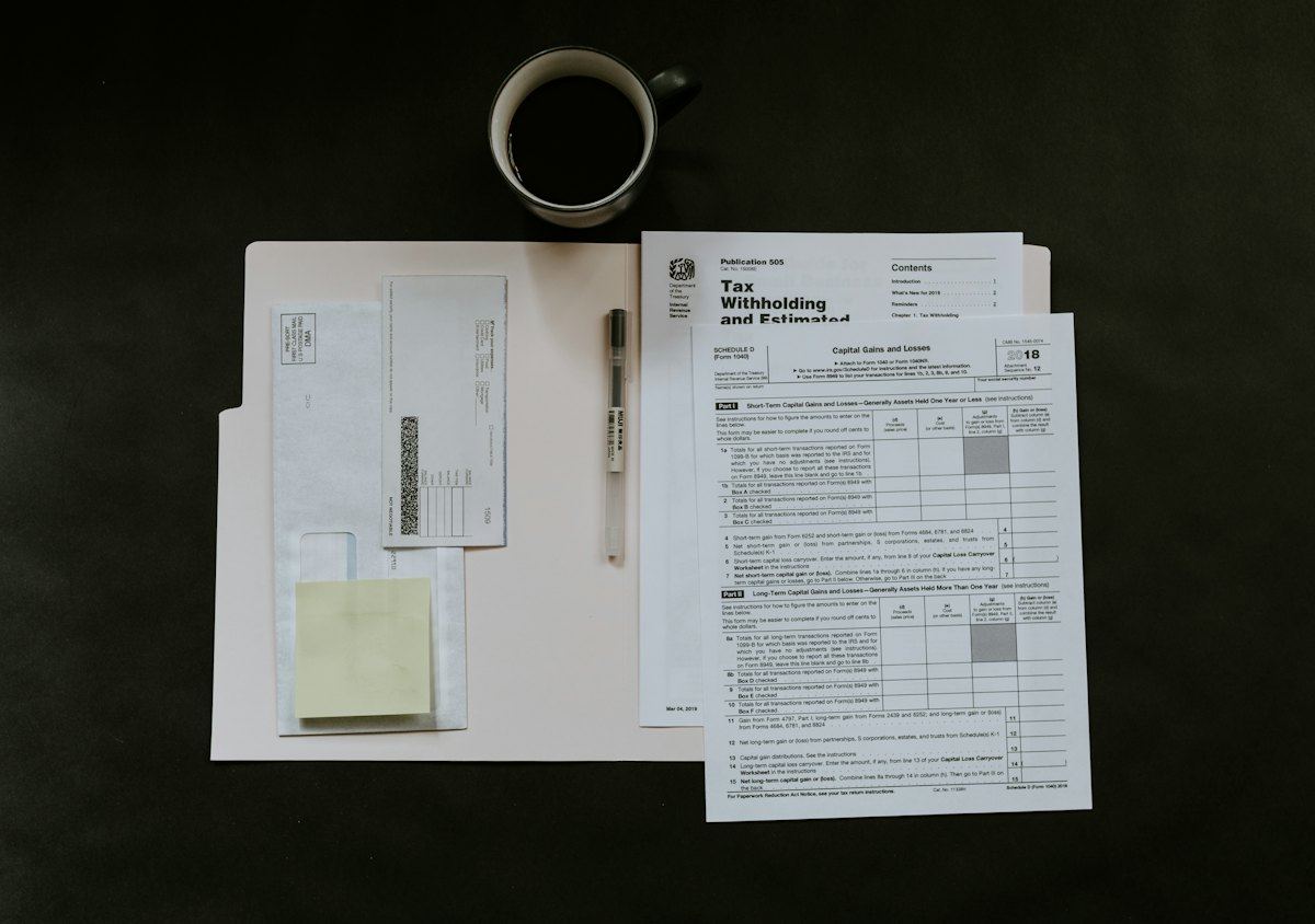 Tax forms, a pen and a coffee mug on a desk